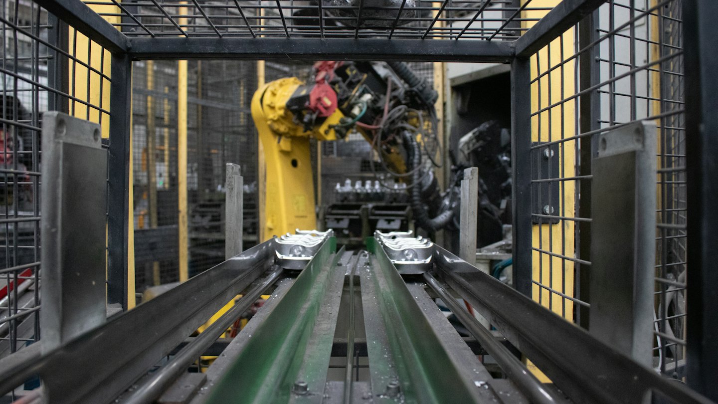 Roboterarm arbeitet an Produktionsstraße mit Förderbändern.