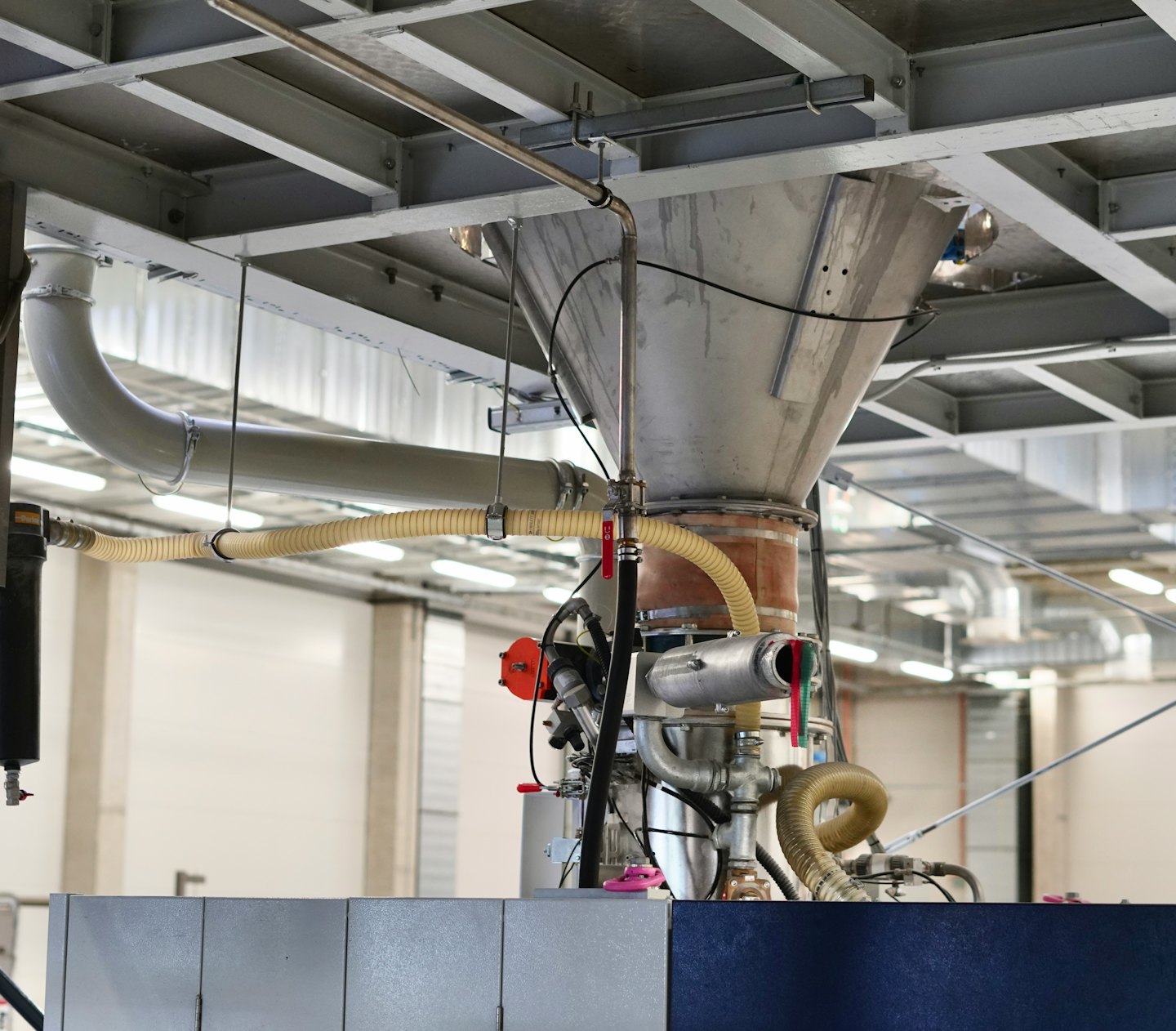 Industrieller Metalltrichter und Rohrsystem in einer Produktionsanlage.